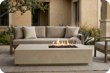 Outdoor patio furniture set featuring a rectangular concrete fire pit table with a burning flame, positioned in front of a beige outdoor sofa with matching cushions.